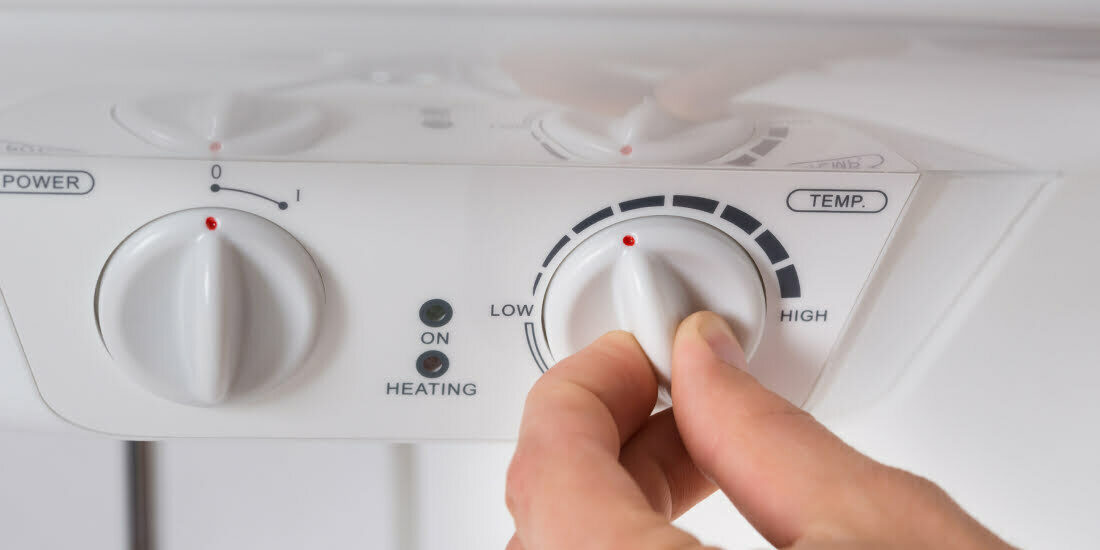 Homeowner adjusting temperature on the boiler control panel