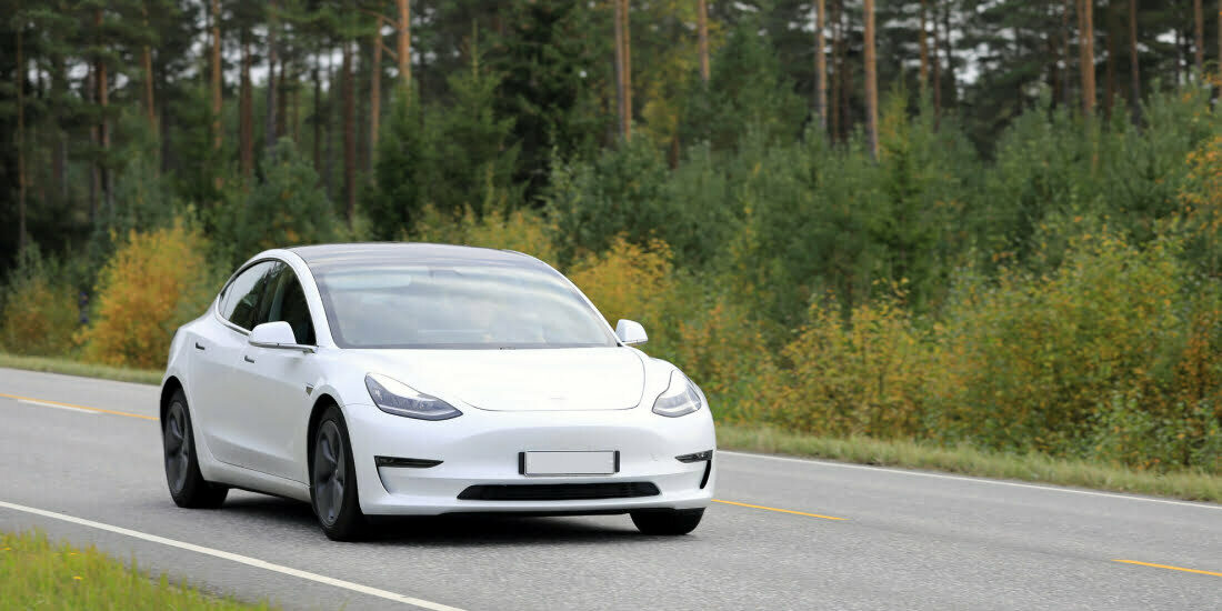 White Tesla driving along a rural road