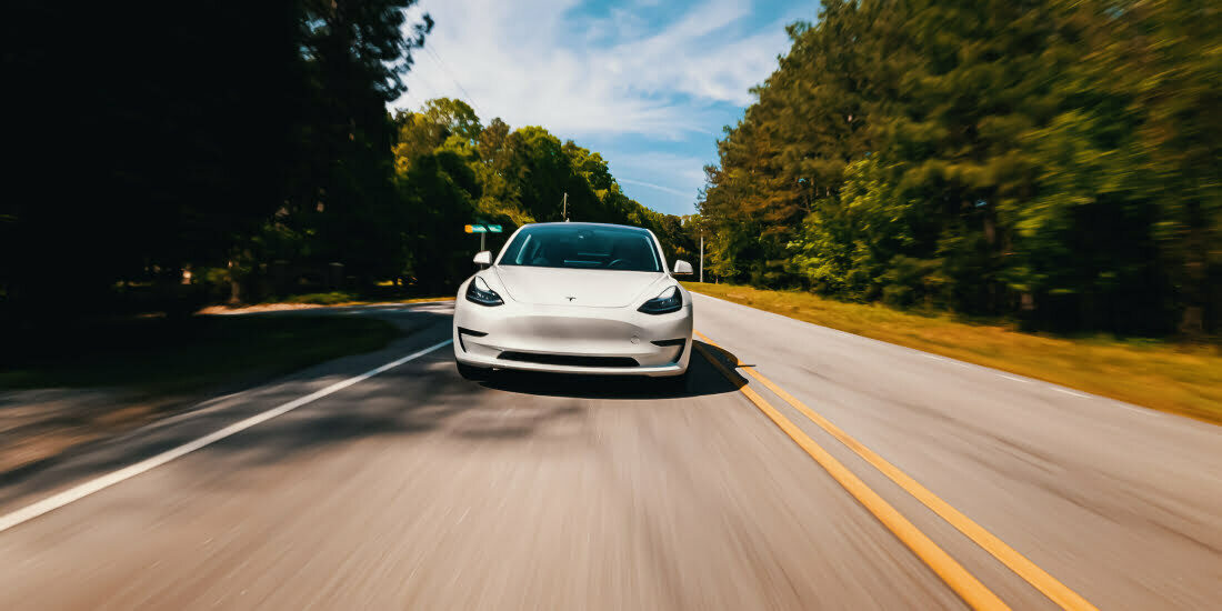 A white Tesla driving on the open road