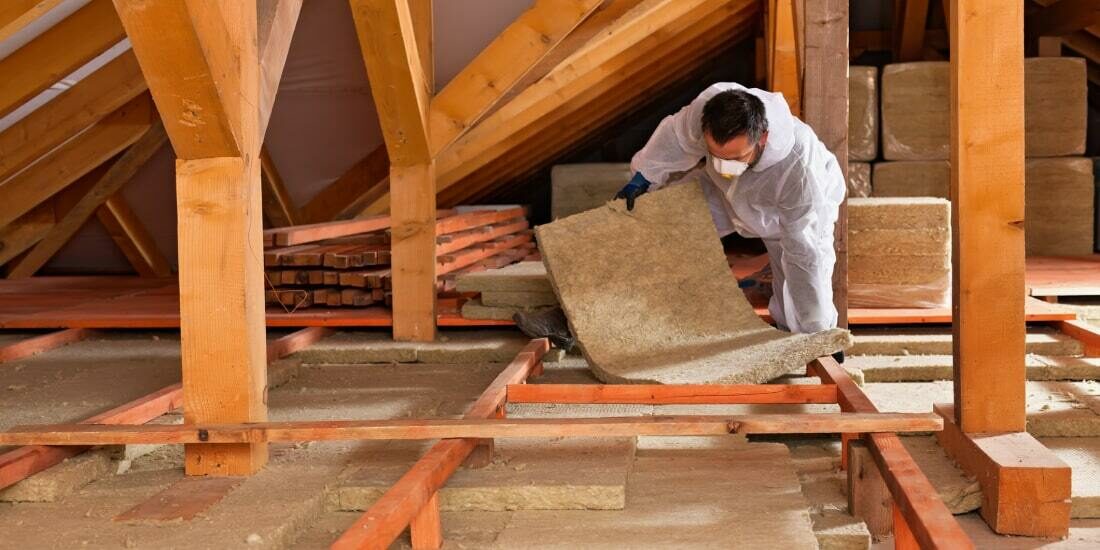 A man installing loft insulation