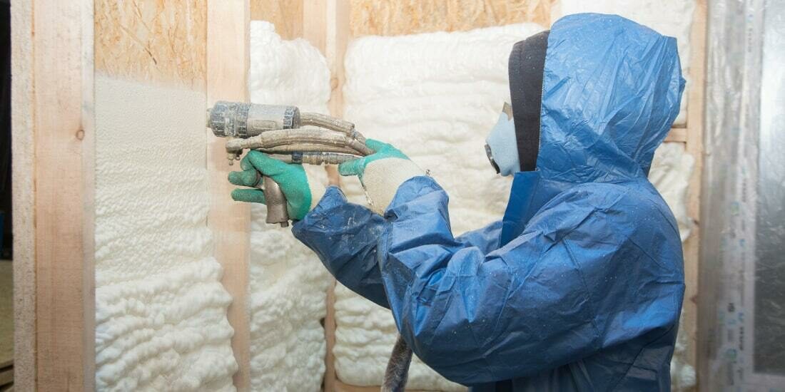 A professional installs spray foam insulation to walls