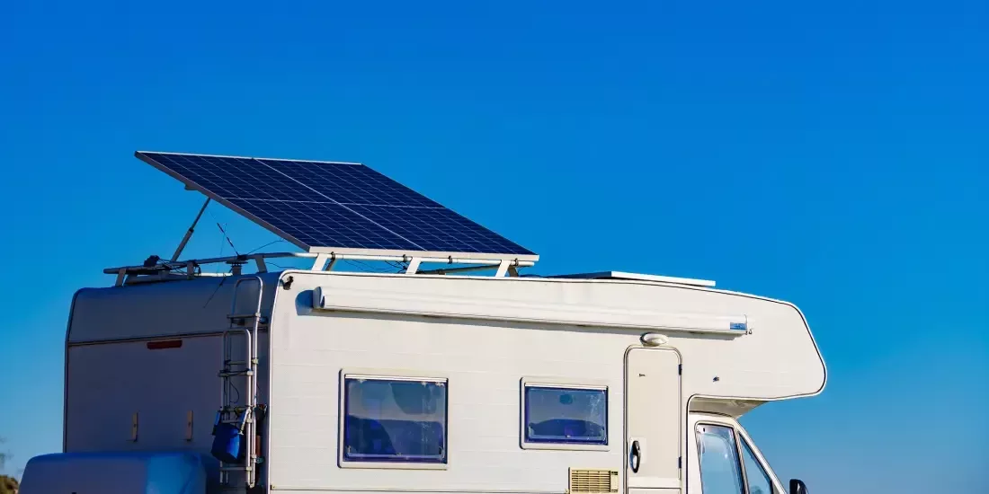 A caravan with a tilted solar panel on the roof