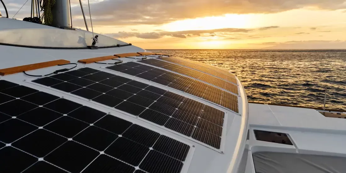 Flexible solar panels on the deck of a ship with a sunset in the background over the sea