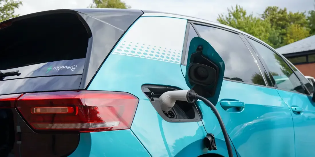 A turquoise EV being charged