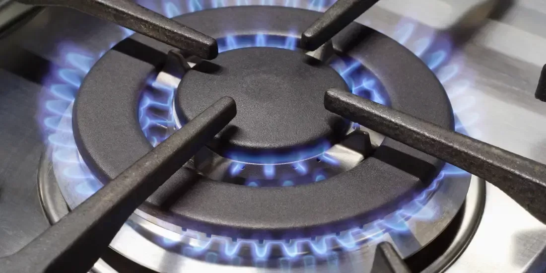 Close up of a gas hob with blue gas rings lit