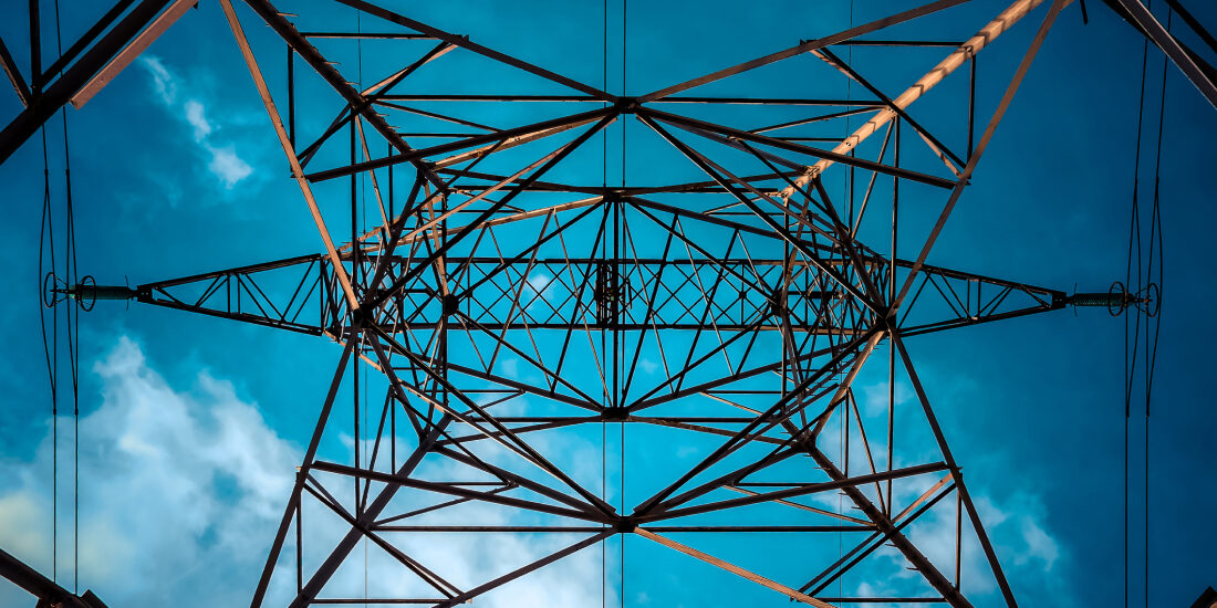 An electricity pylon from below looking up at a dark blue sky