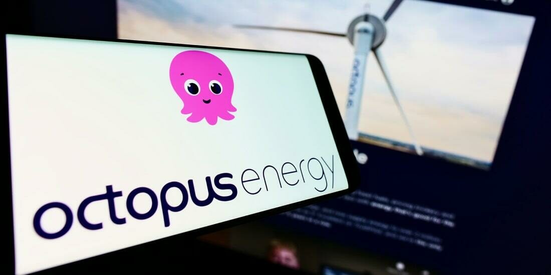 Octopus Energy logo on a mobile phone next to a laptop with a wind turbine