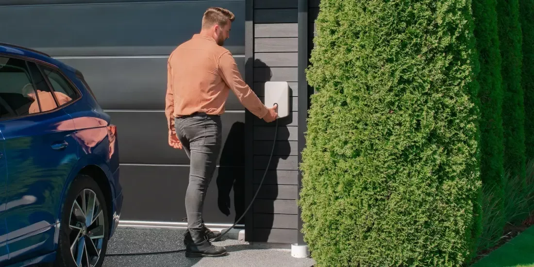 A man presses a button on his home EV charger in his drive