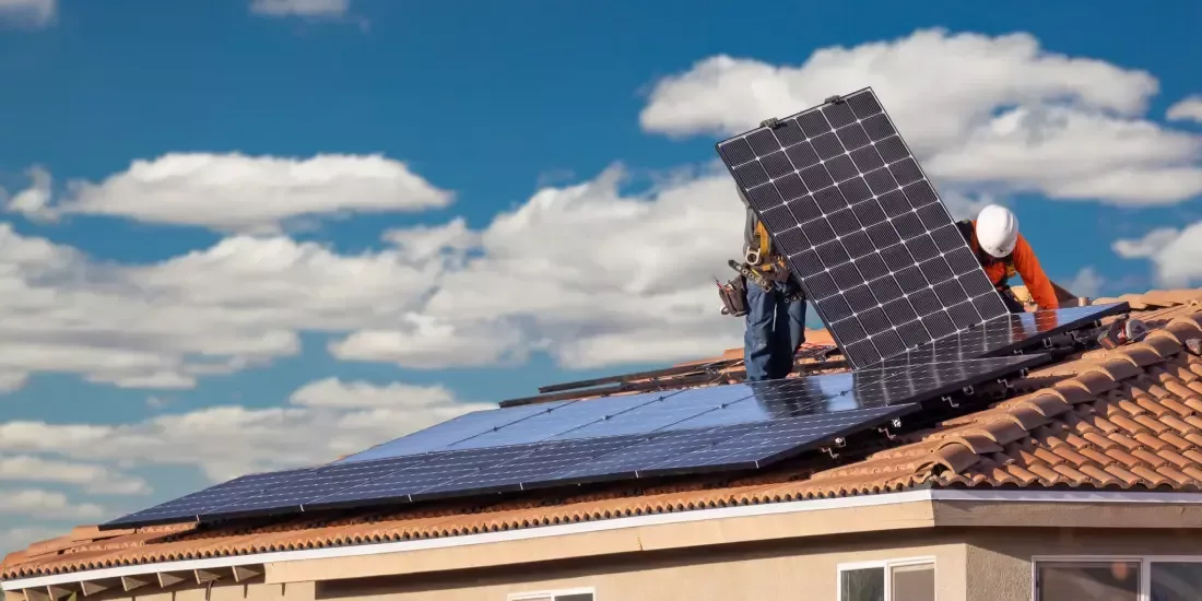 Two installers fitting solar panels on the roof of a building