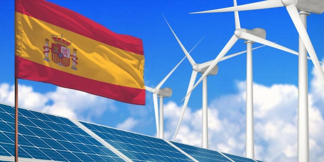 Spanish flag above solar panels and wind turbines