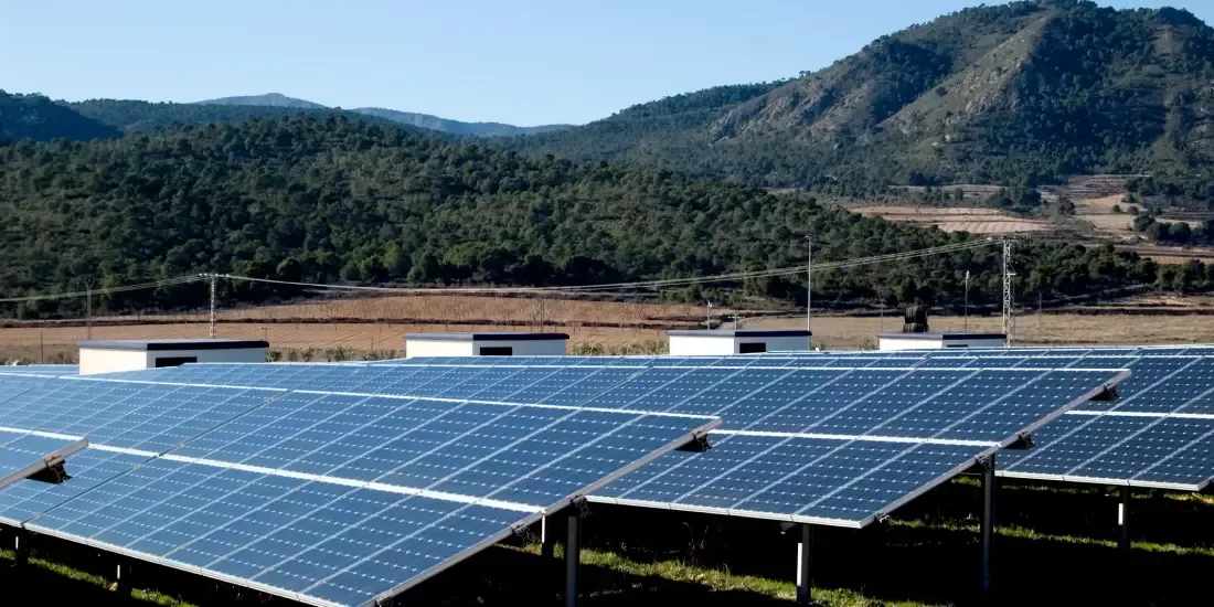 A solar plant within Spain with green hills in the background