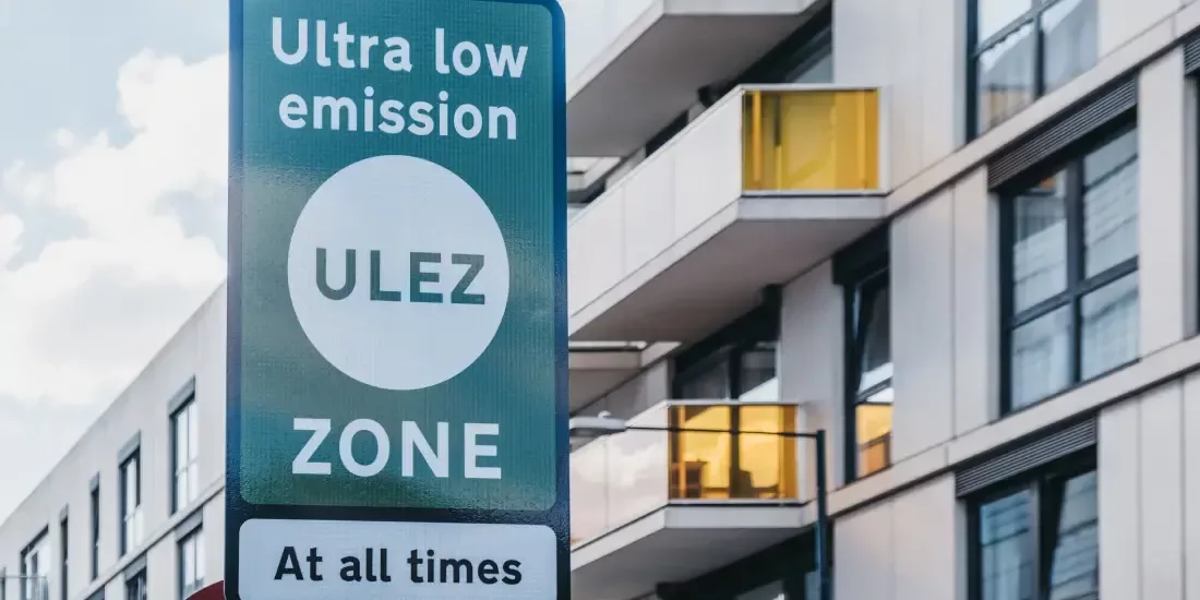 A ULEZ road sign beside a modern block of flats