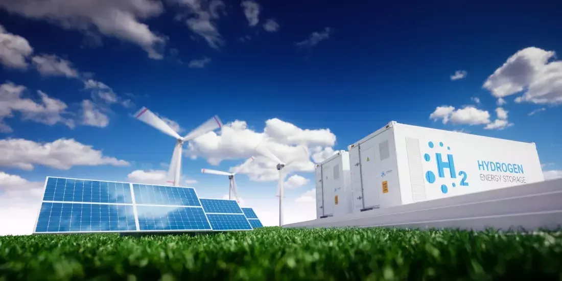 Solar panels, wind turbines and hydrogen storage on grass against a blue sky backdrop